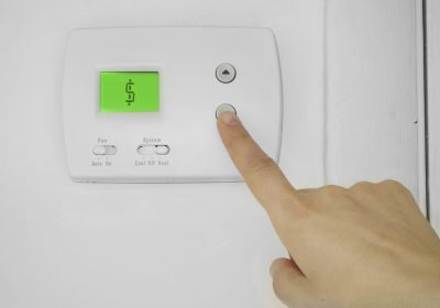 A person pressing a button on a thermostat