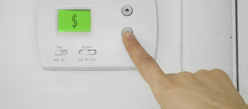 A person pressing a button on a thermostat