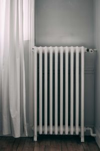 Old heater in a room next to a white curtain