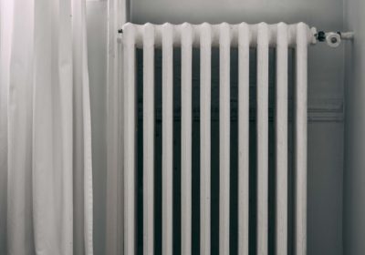 Old heater in a room next to a white curtain